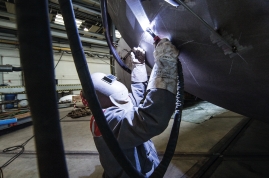 Kniend schweißen auf hartem Betonuntergrund in Zwangslage, beide Hände nach oben gestreckt 